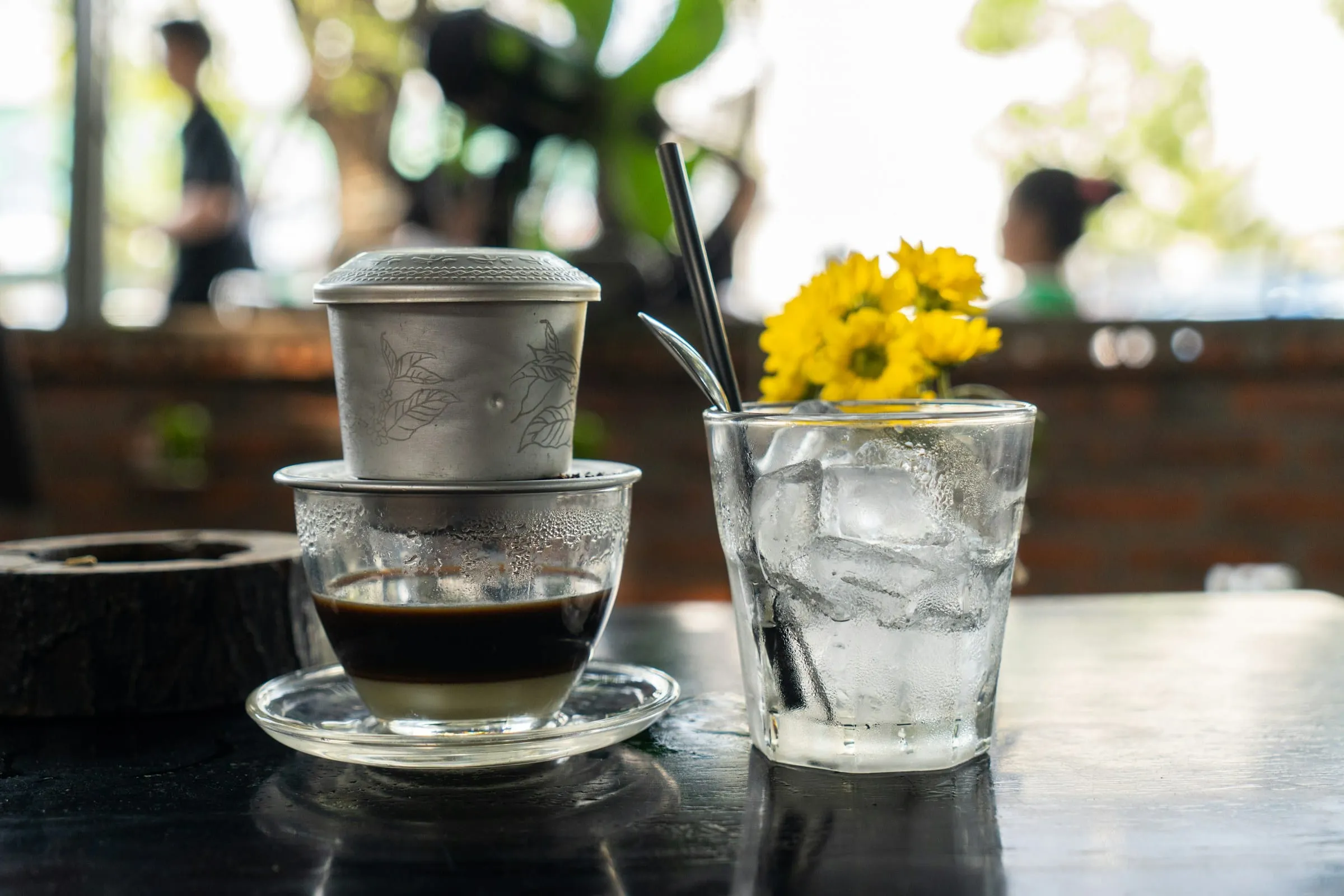 Vietnamese phin filter coffee and a glass of iced water on a café table
