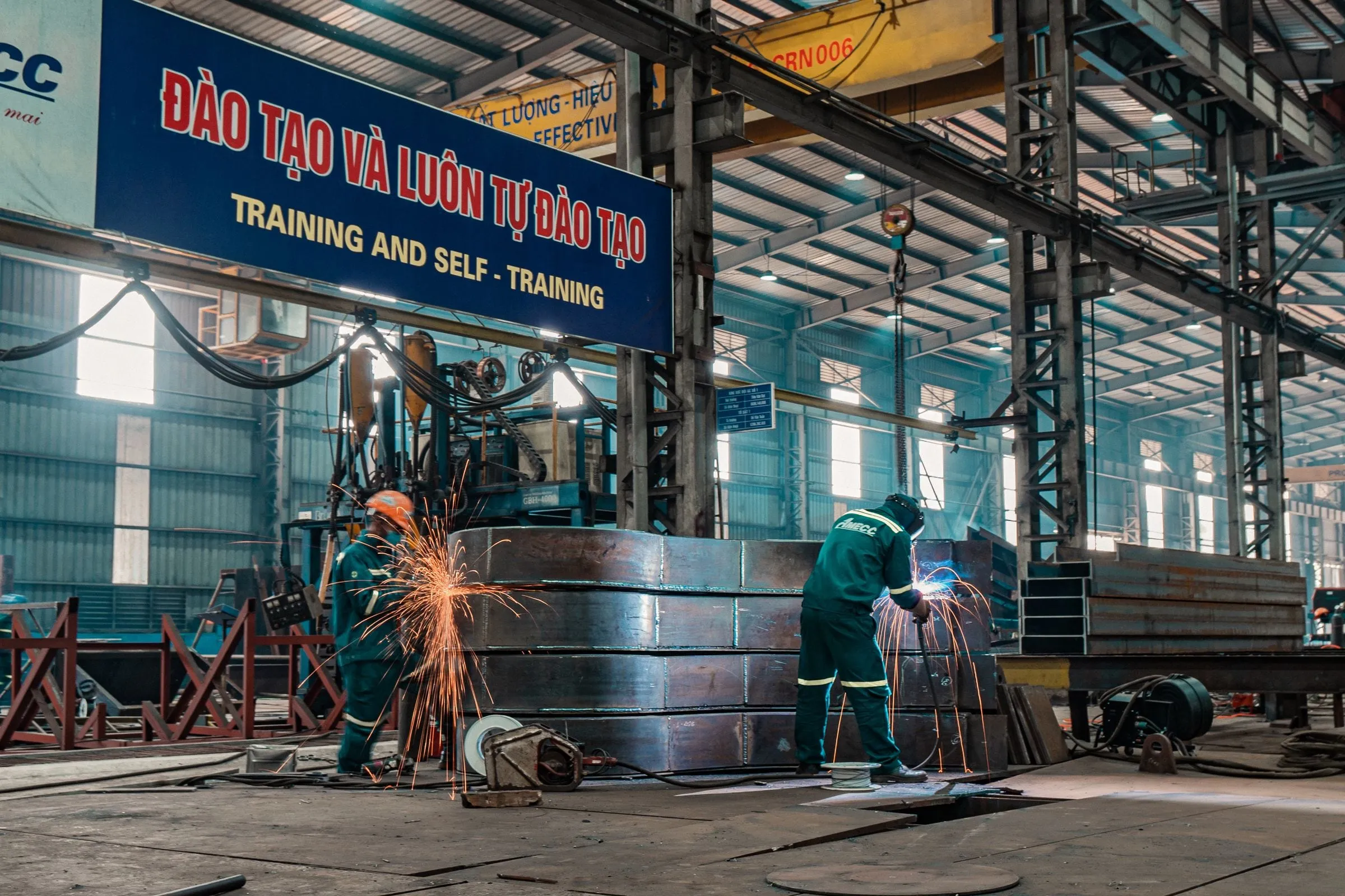 Workers welding metal structures in an industrial workshop