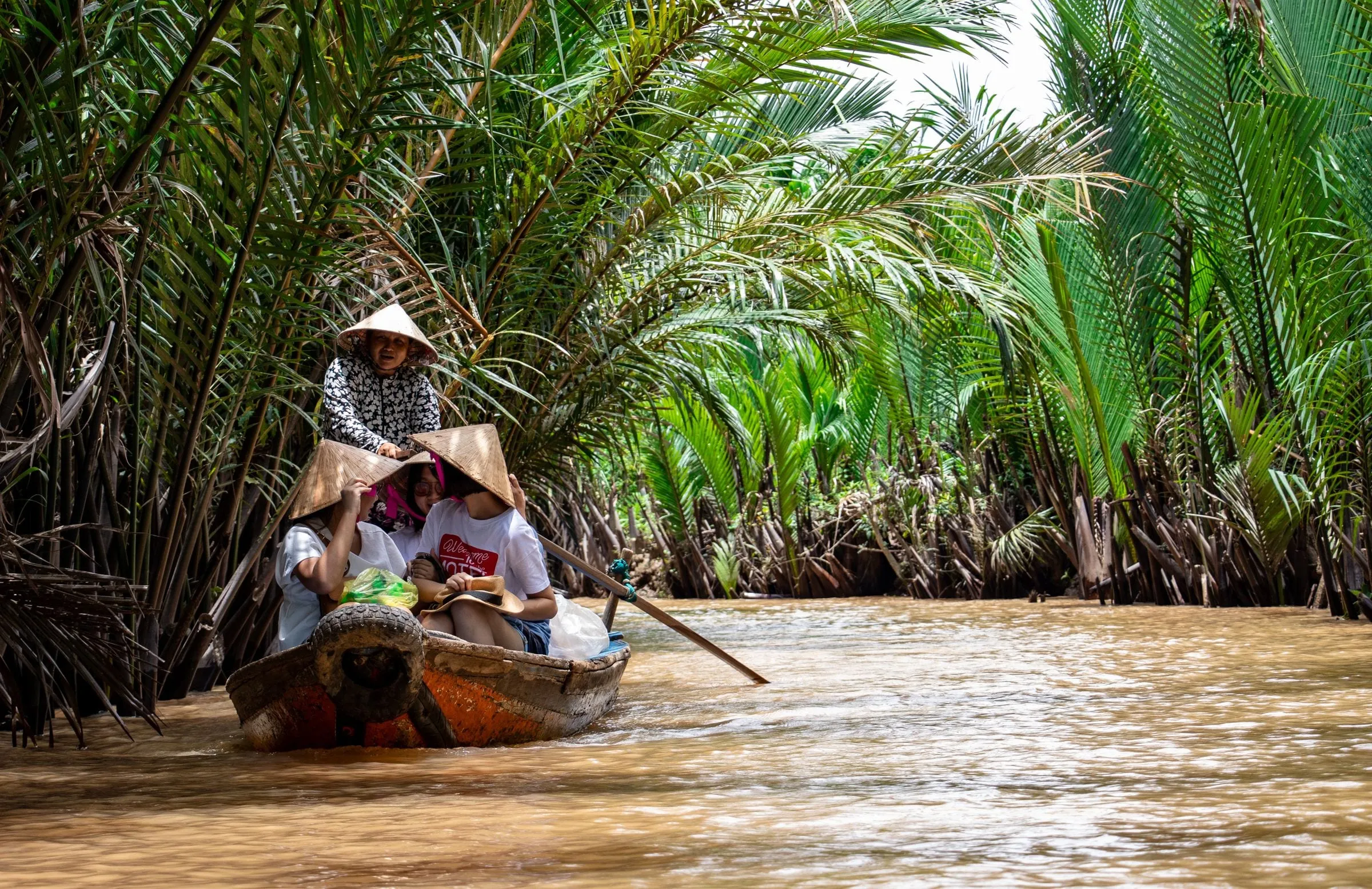 A boat on a palm-lined waterway in the Mekong Delta