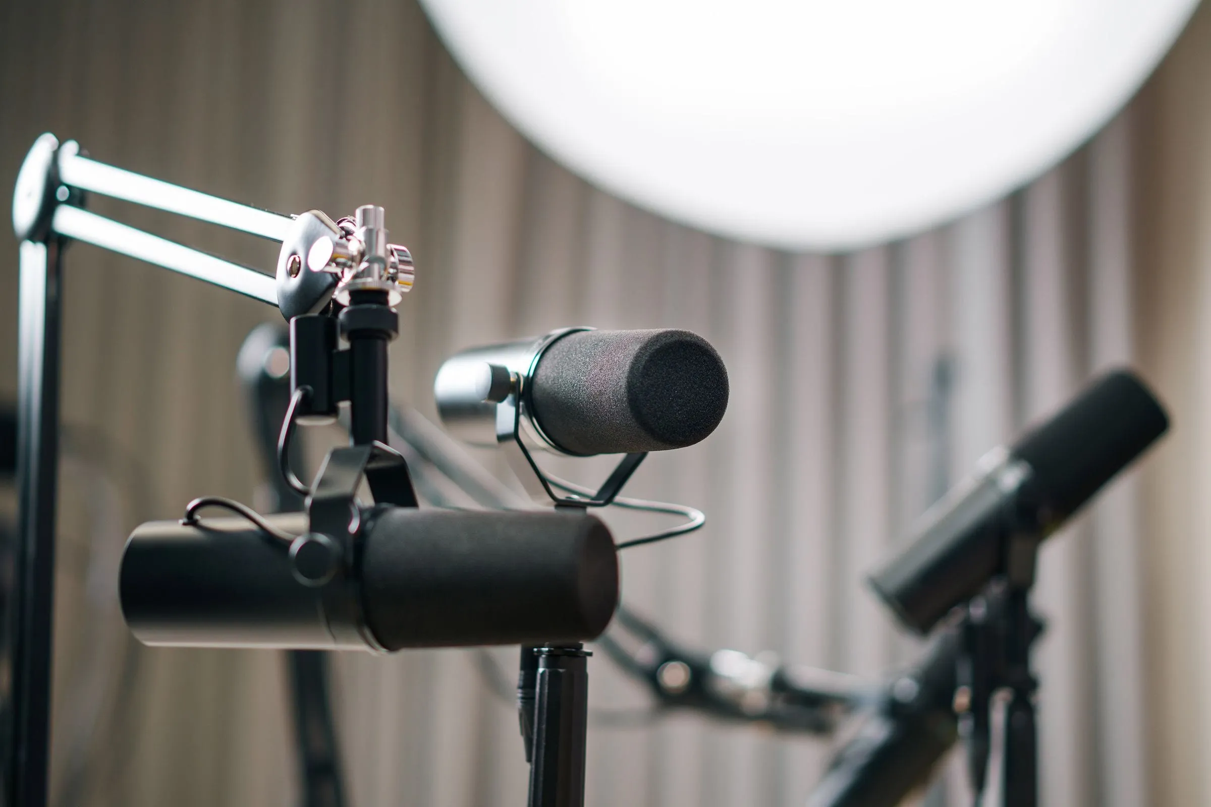 Podcast microphones on boom arms beside a studio light