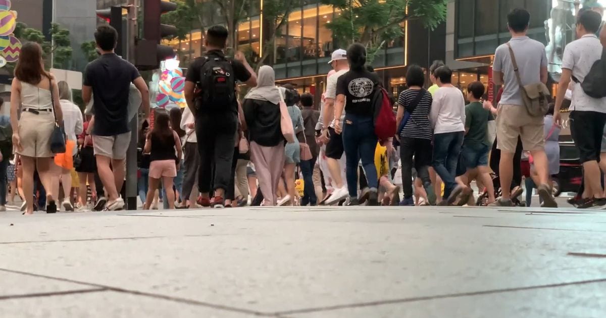 Pedestrians crossing a street in a shopping district in Singapore